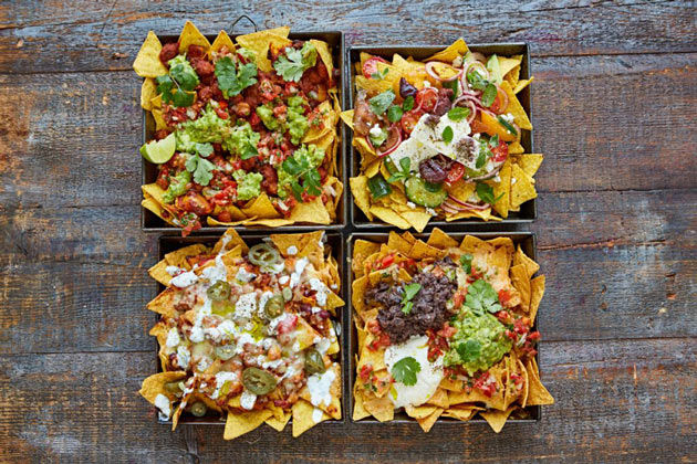 4 dishes of nachos with different toppings on top
