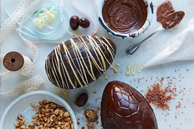 chocolate eggs being decorates with white drizzle and crunchy nut