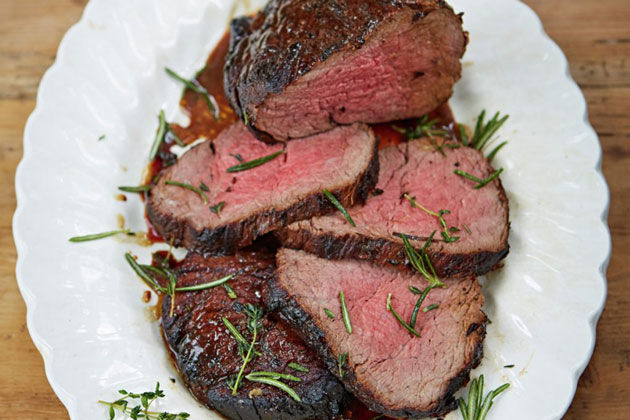 slices of steak with marinade on top and rosemary