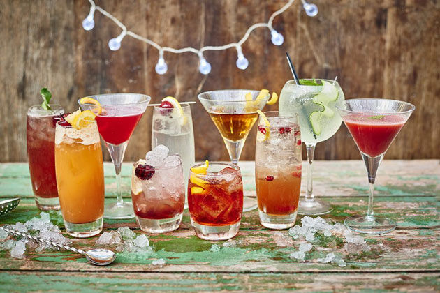 an array of cocktails with ice and fruit garnishes