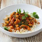 lamb and chickpea curry on rice with herbs on top