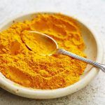 a plate of turmeric with a spoon dipped in it