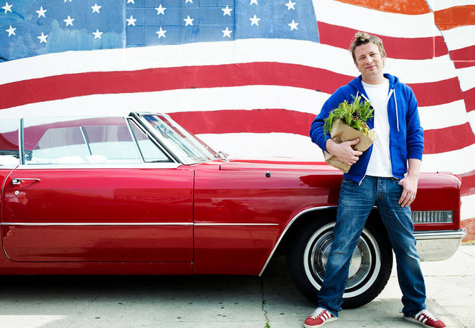 Jamie standing in front of a red convertible and Amercian flag