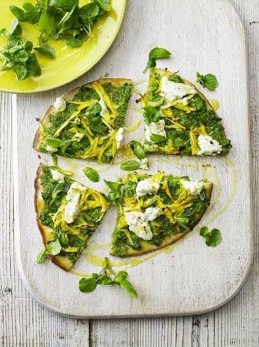 Sliced spring green pizza with herbs sprinkled on top