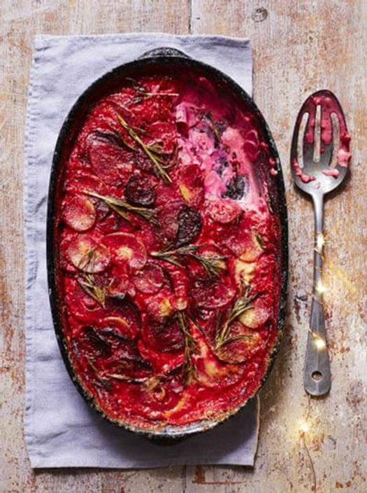 Black baking tray filled with beetroot gratin with a serving spoon on the side
