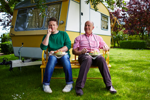 Jamie and his dad sitting in front of a caravan