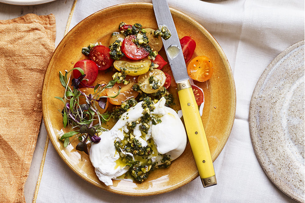 Summer recipes - beautiful burrata on a plate with tomatoes and pesto