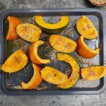 Pumpkin chopped into wedges on a baking tray, ready to go into the oven with spices to create a gorgeous roasted pumpkin recipe