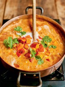 Pumpkin and chickpea curry in a bubbling pot with coriander on top