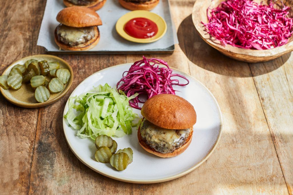 A burger and salad on a plate, surrounded by more burgers and more salad