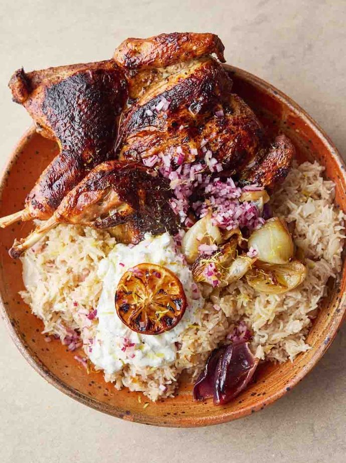Grilled chicken leg on a bed of fluffy rice with tzatziki and charred lemon