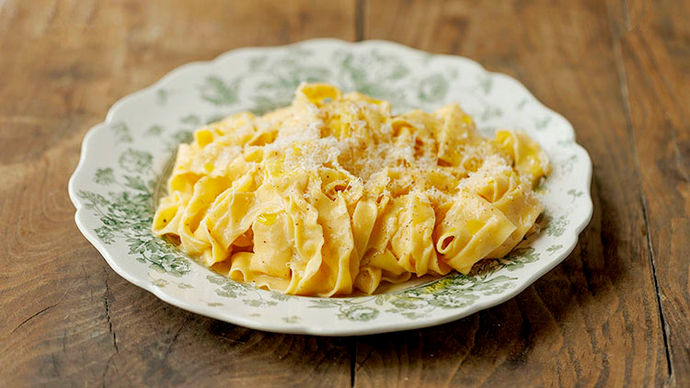 A bowl of creamy pasta with Parmesan shavings on top