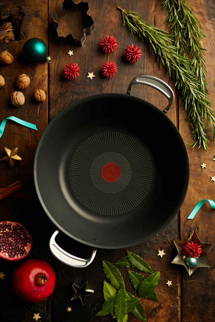 Tefal Big Batch pan surrounded by Christmas decorations like rosemary, ribbons and stars