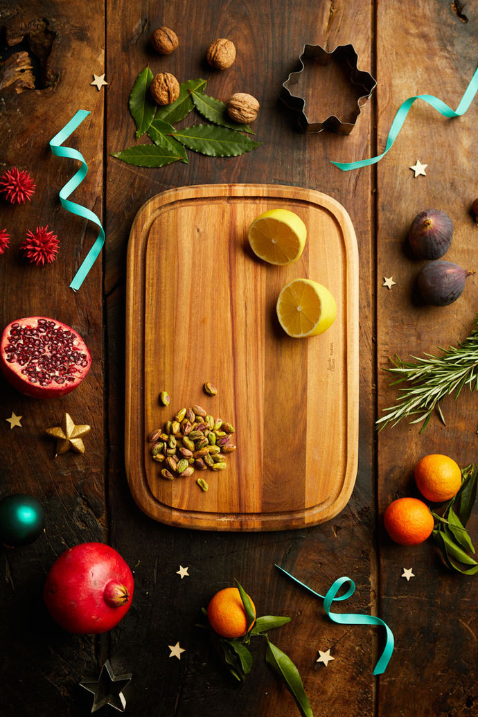 Tefal chopping board with lemons and nuts, surrounded by pomegranate, tangerines, rosemary and ribbons