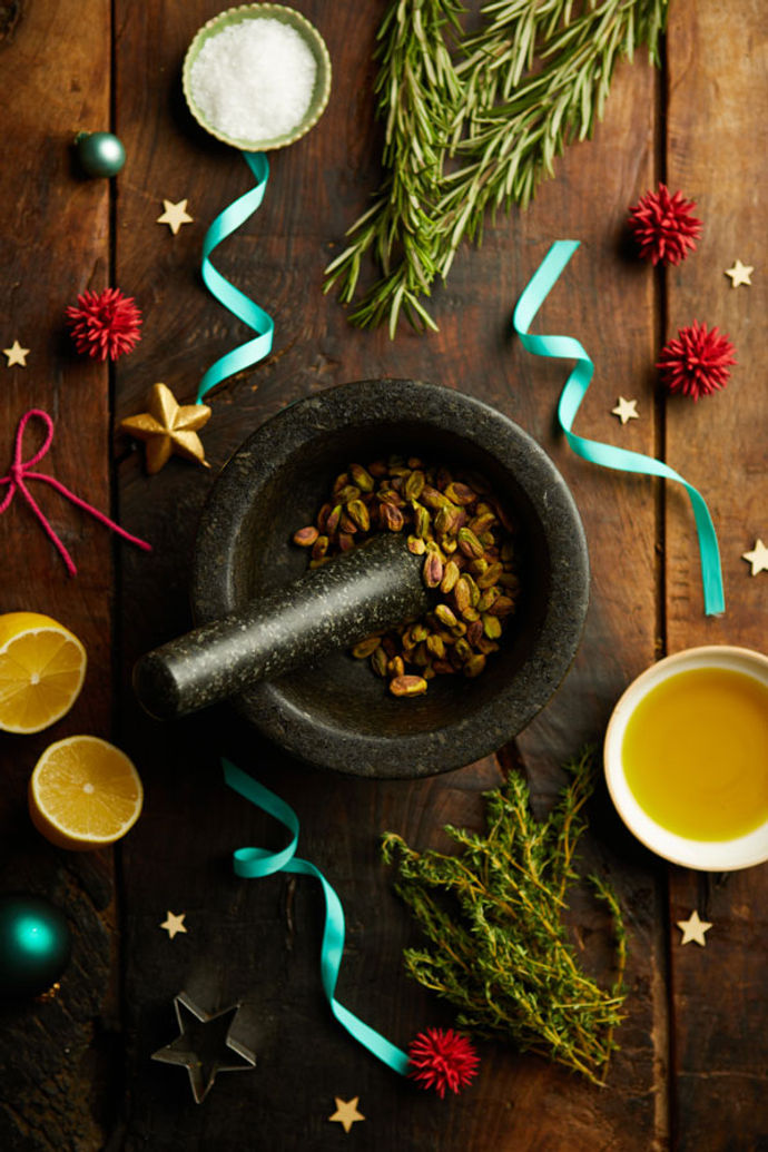 Pestle and Mortar crushing pistachios, surrounded by lemons, ribbons and Christmas decoration