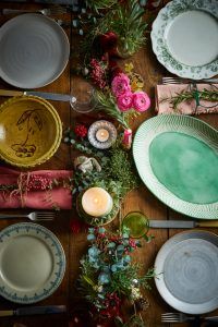 Mediterranean-inspired dinner table setting with colourful plates, candles and foliage