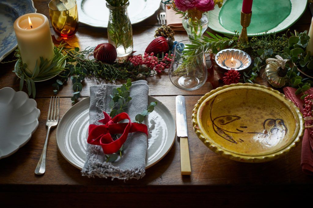A beautifully-laid Christmas Day dinner table with colourful crockery, ribbons and foliage for decoration