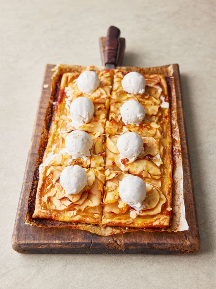 A rectangular pastry tart topped with cooked apple and balls of vanilla ice cream