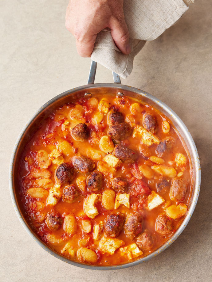 Frying pan with giant beans and sausage pieces in a red sauce