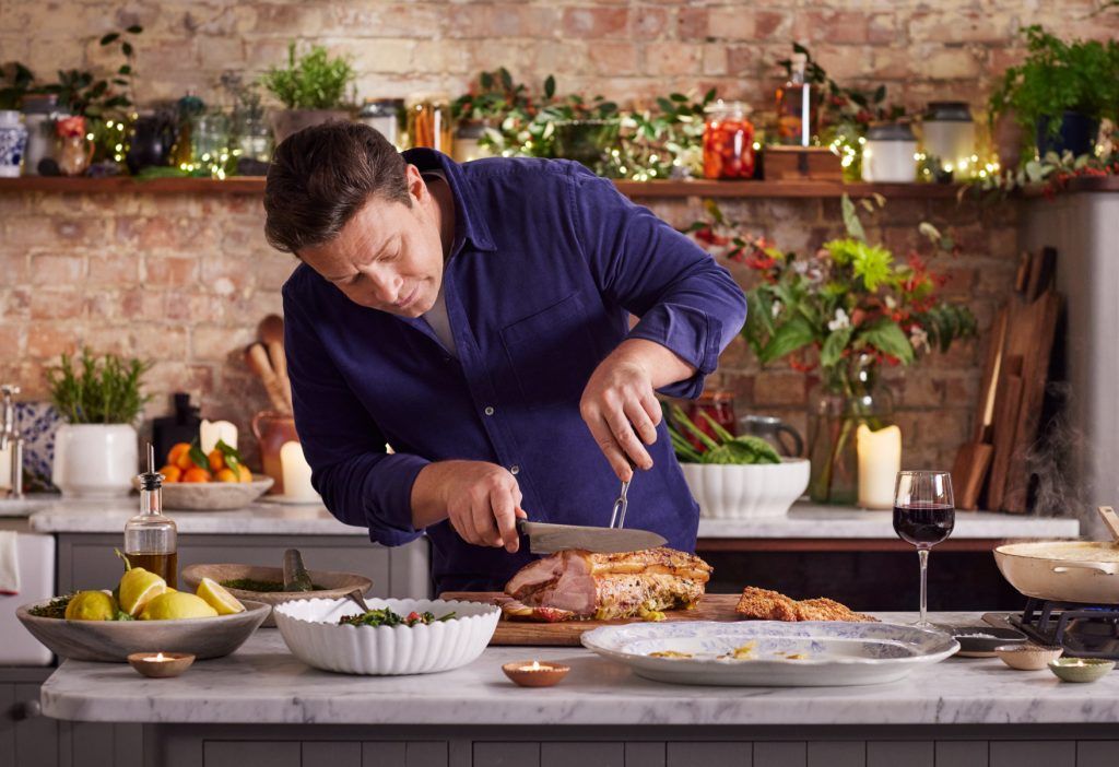 Jamie Oliver carving a roast pork for New Year's Eve dinner with festive decorations for the occasion
