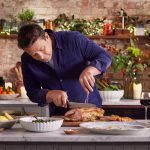 Jamie Oliver carving a roast pork for New Year's Eve dinner with festive decorations for the occasion