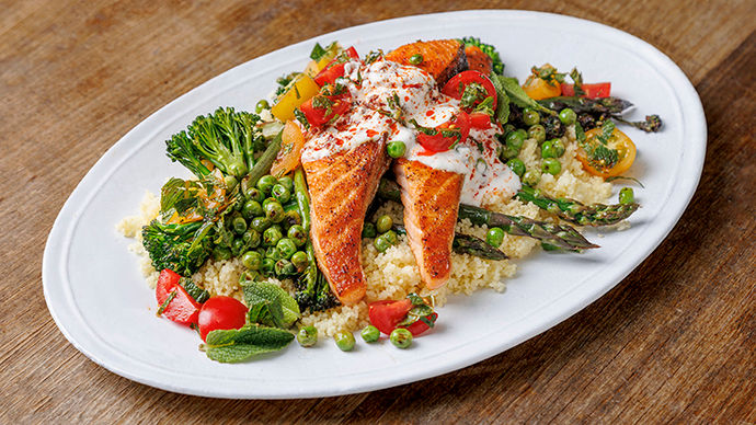 Salmon fillet with couscous and vegetables like broccoli, peas and tomatoes