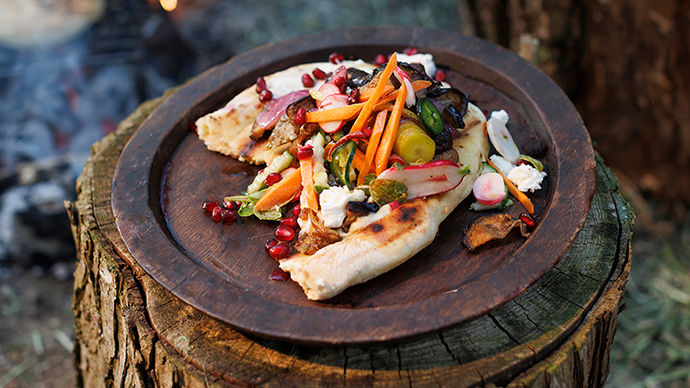 Mushroom and aubergine shawarma served on a brass plate with pickles, carrots and dressing