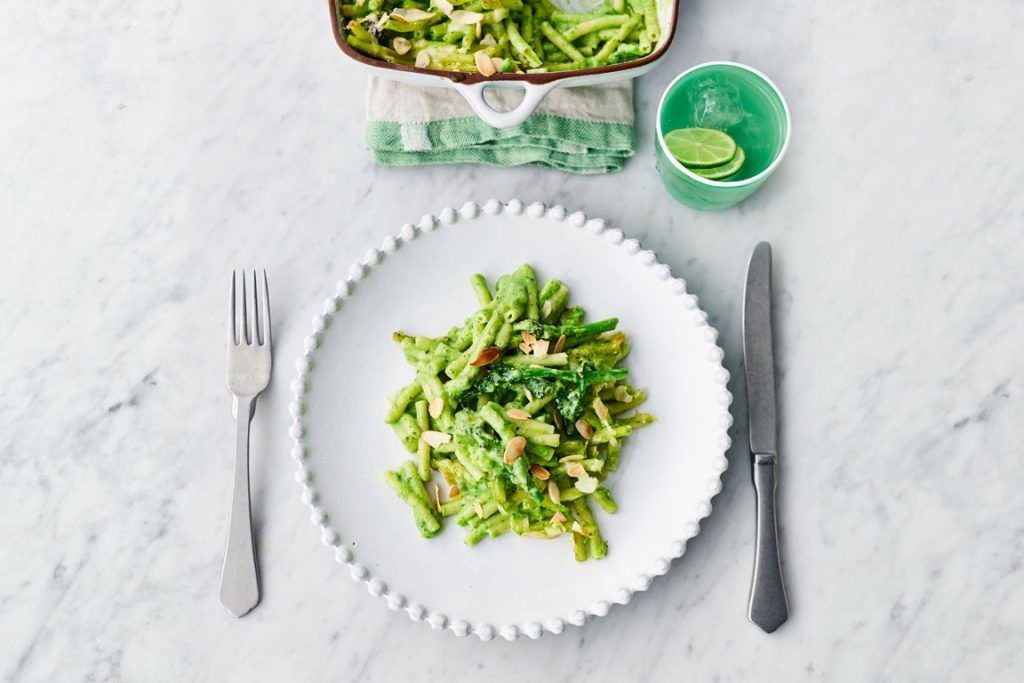 How to use up spring onions - a serving of greens mac & cheese with a pot of limes to the top right of the plate, and an oven tray with the rest of the pasta above