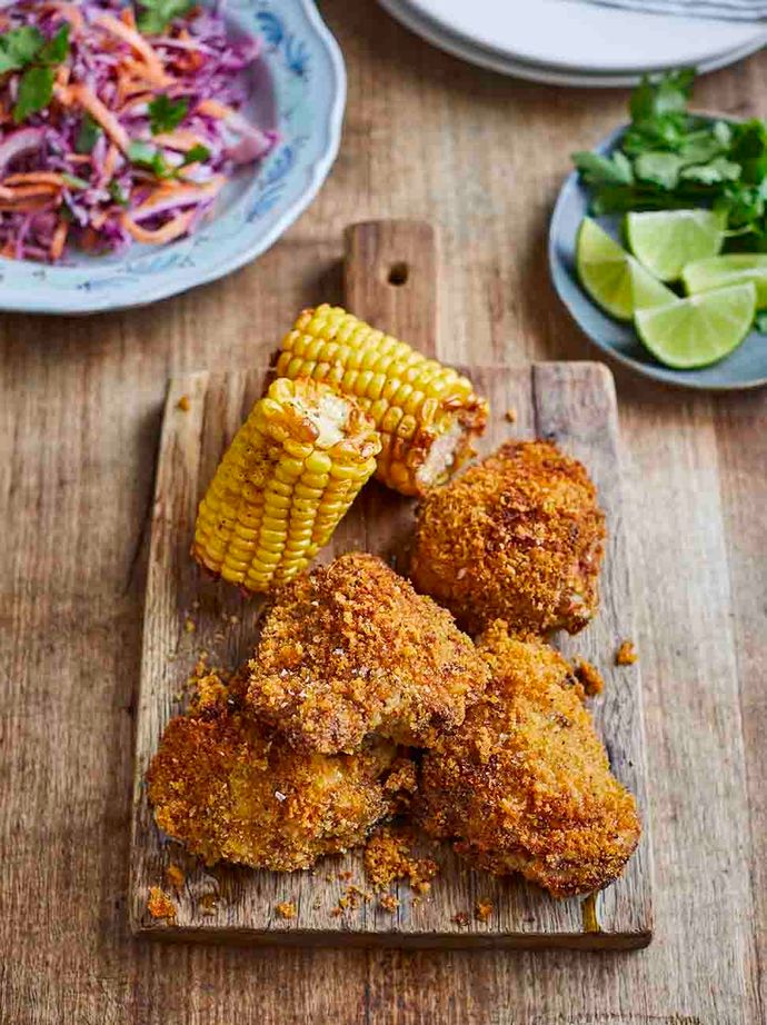Crispy breaded chicken thighs with corn on the cob, coleslaw and salad.