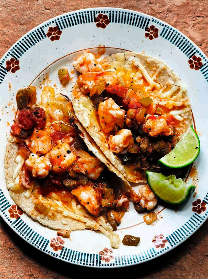 A plate of prawn and cheese tacos with two slices of lime