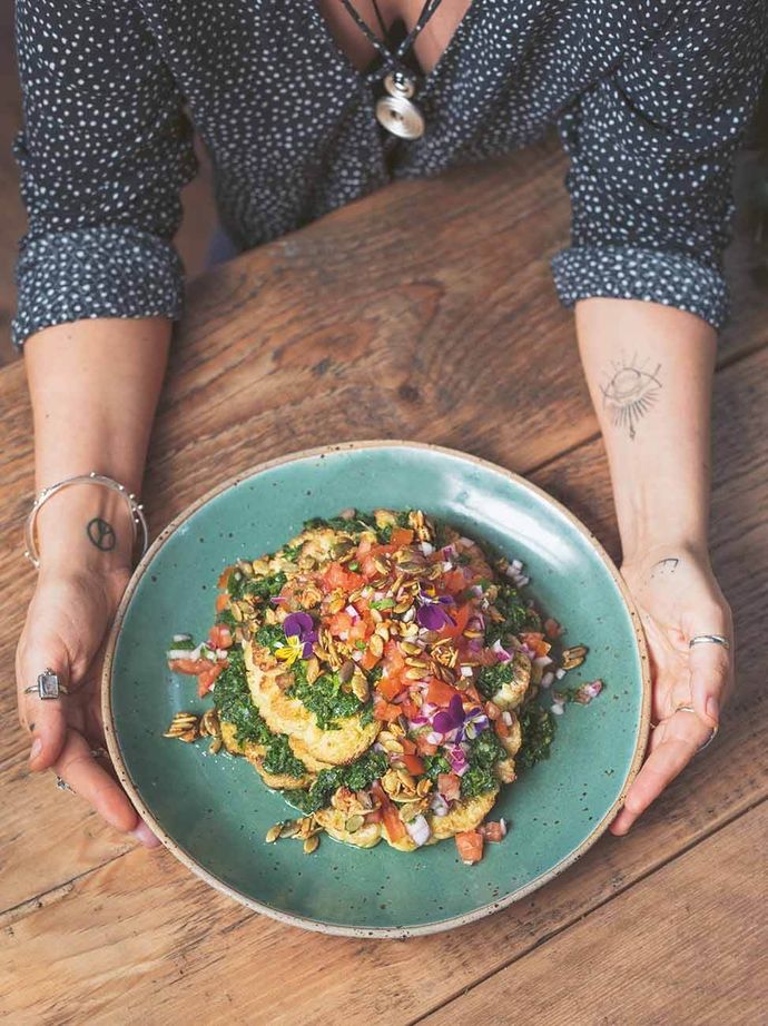 Franki Paz holding a plate of Chimichurri cauliflower loaded with pico de gallo from the cookbook 'Plant Feats'