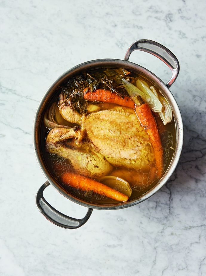 Poached chicken - A whole chicken in liquid in a pot with vegetables. From Simply Jamie