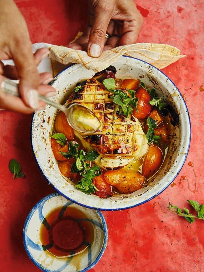 Whole grilled halloumi with apricots in a bowl. Somebody holding up the bowl with a cloth, and spooning the food with the other hand.