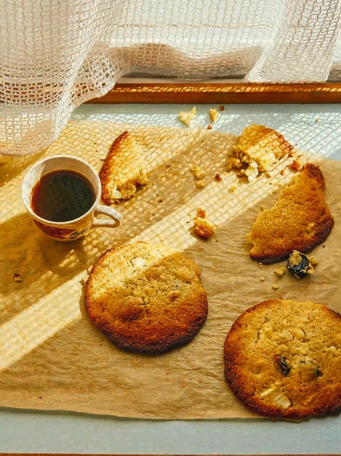 Feta, cherry and white chocolate cookies on a wood board with a cup of black coffee