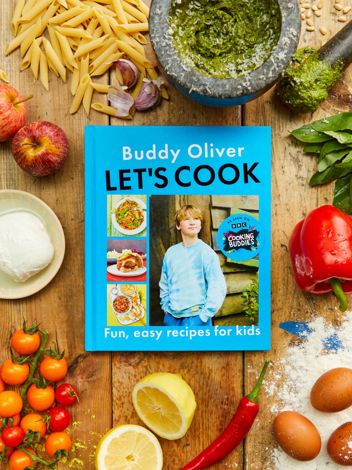 Let's Cook, cookbook by Buddy Oliver, surrounded by ingredients like lemon, tomatoes, pesto and pasta
