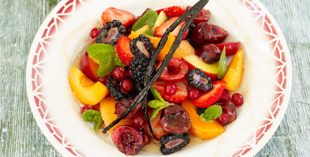 chopped fruit in a bowl with a vanilla stick in and syrup