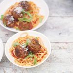 spaghetti in tomato sauce with meatballs and parmesan on top