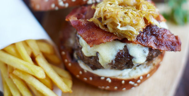 beef burger with melted cheese on top, bacon and onions with chips on the side
