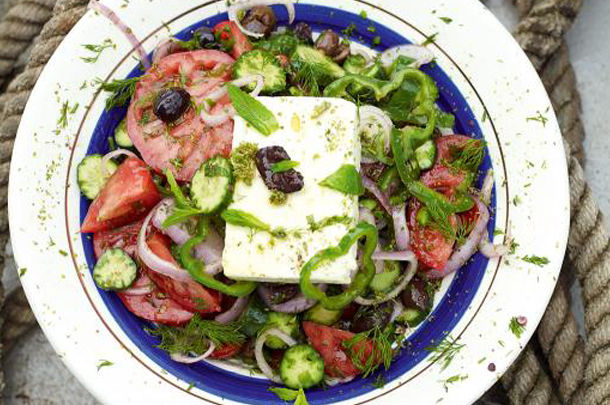 greek cheese with salad and herbs on top with olives