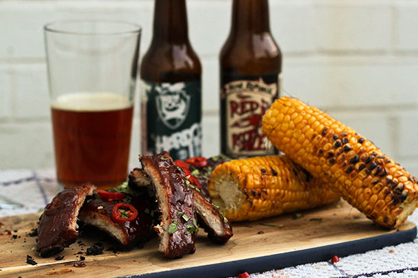 bbq corn on the cob with ribs covered in chilli next to beer