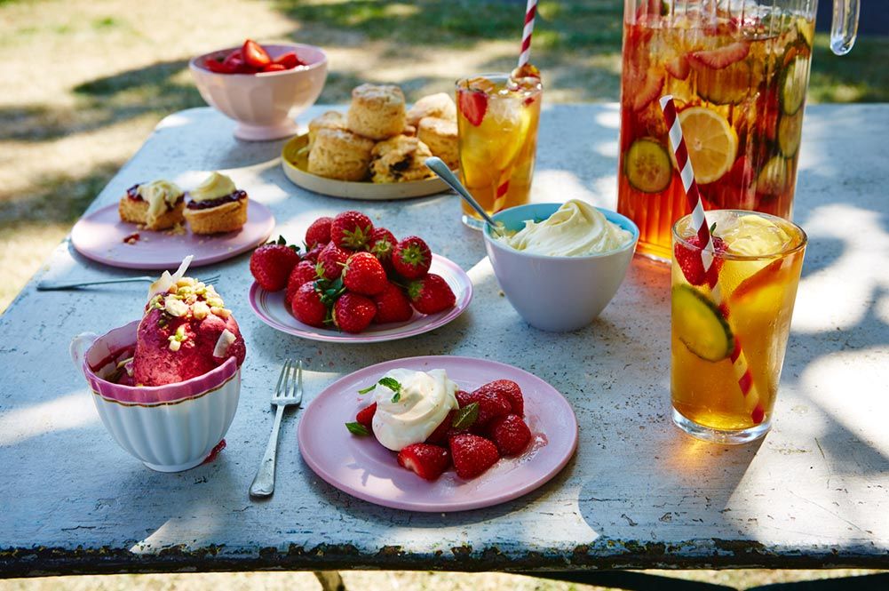 strawberries with cream on top and fruit iced tea with scones
