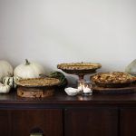 thanksgiving display with pies surrounded by pumpkins and squash