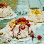 3 different pavlovas with fruit on top and fruit sauce over it