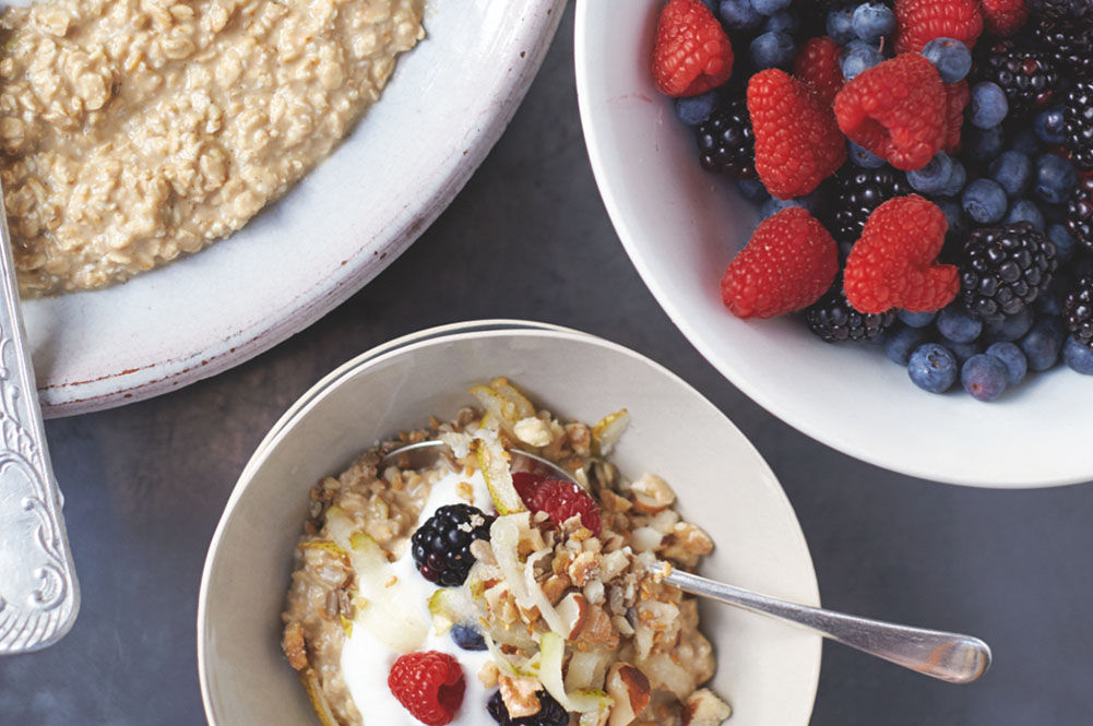 Healthy breakfast with bowls of granola, porridge and fruit