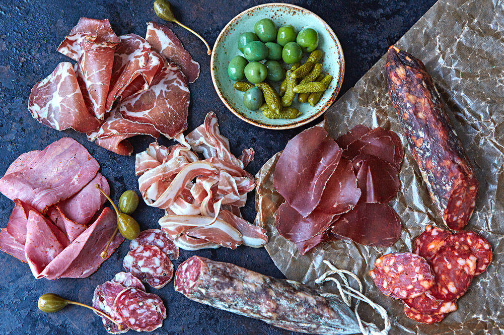 british charcuterie - a spread of different hams with olives and gherkins