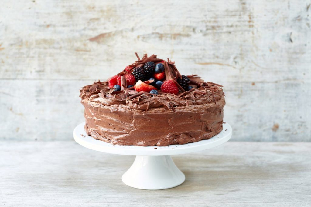 chocolate cake with berries on top and on a cake stand with chocolate shavings