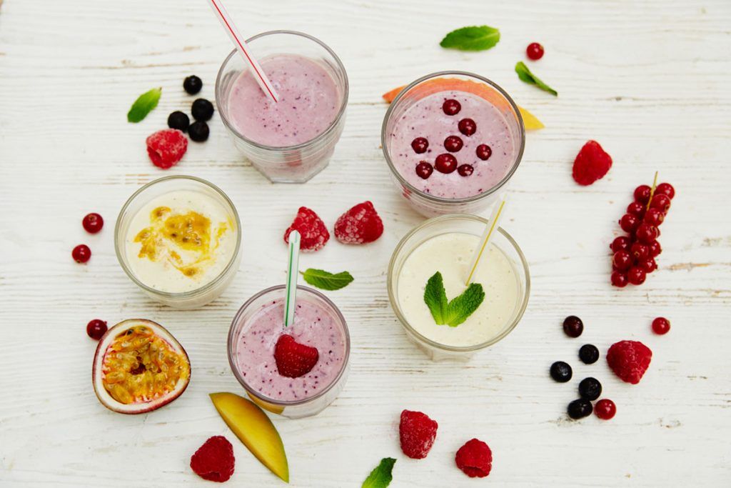 smoothies flat lay with fruit scattered around the glasses