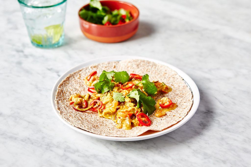 masala scrambled egg with chilli and coriander on top, on top of a wrap