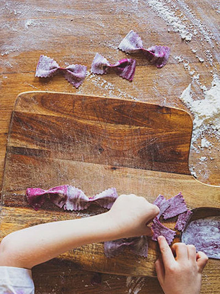 child making fresh purple pasta bows