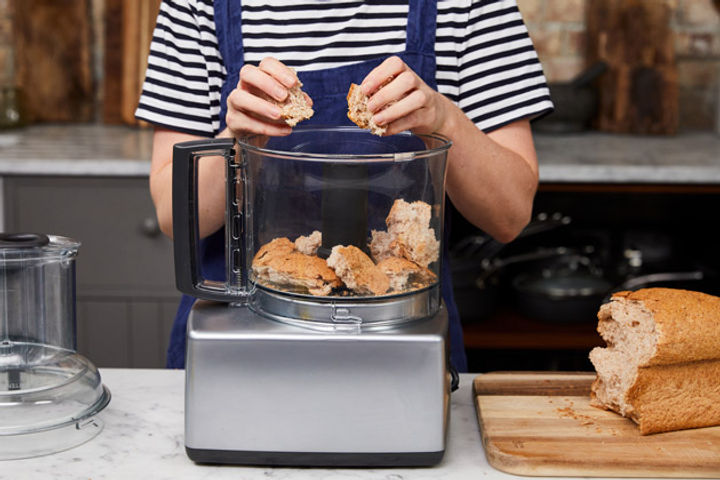 Person tearing up a load of bread into a food processor